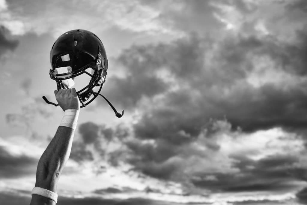 player holding football helmet up in air black and white